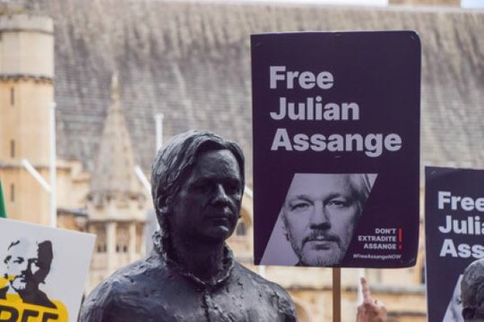 Statue von Julian Assange bei einem Protest in England, dazu Schilder, die für seine Freilassung appellieren..…             (Bild: RSF)