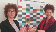 «Mit dem dezidierten Charme einer ‘valerusa da Lumnezia’»: Fabiola Carigiet (r.) überreicht Anita Capaul die «Plume de paon». (Bild zVg)